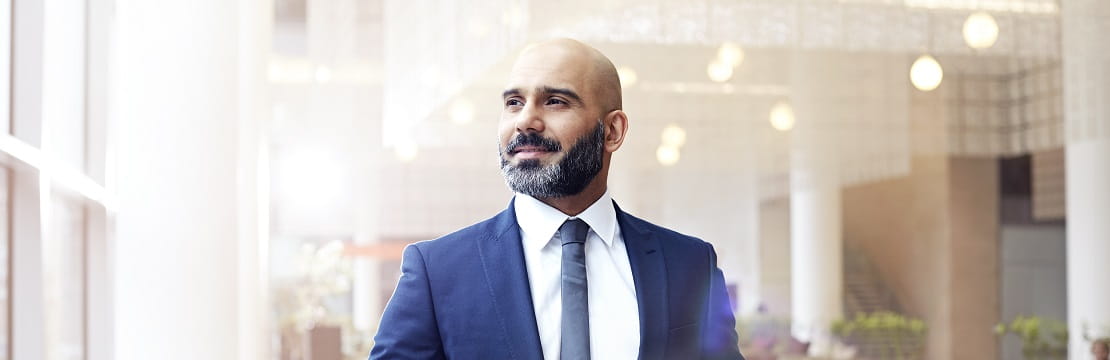 A businessman in professional attire stands in a modern office